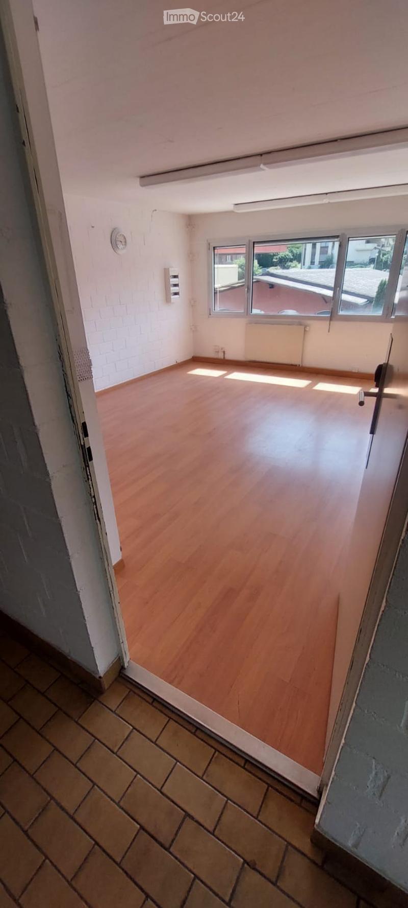 Empty room with wooden flooring, white walls, and large windows letting in natural light. No furniture or equipment present.