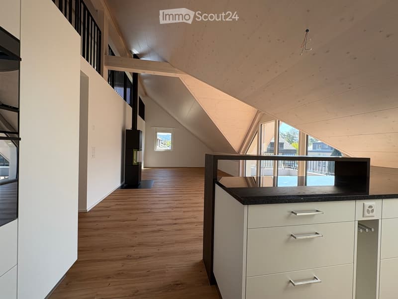 Modern, open-concept space with wooden flooring, white walls, and a sleek black countertop with integrated cabinets and drawers.