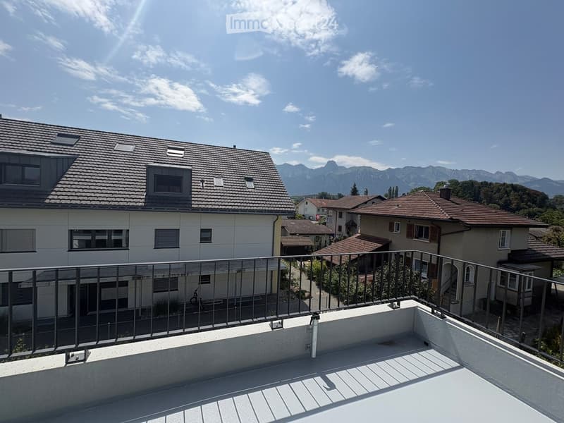 Balcony overlooking a residential area with houses and a mountain view in the background.