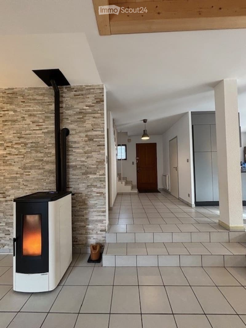Modern hallway with tiled flooring, white walls, and a visible fireplace on the left side.