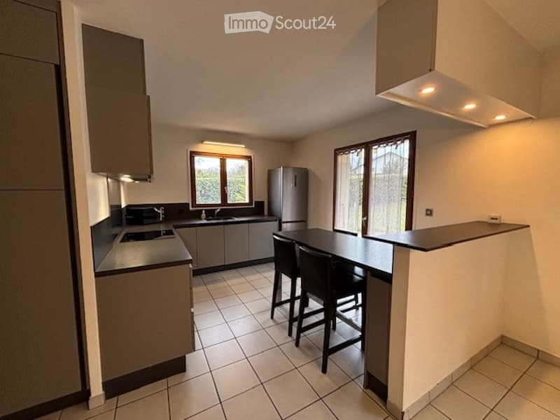 Modern kitchen with grey cabinets, stainless steel appliances, and a central island with bar stools.