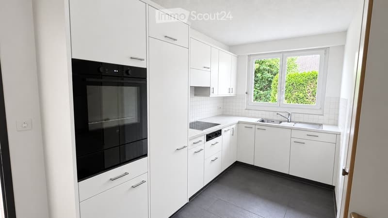 Modern kitchen with white cabinets, black oven, and stainless steel sink.
