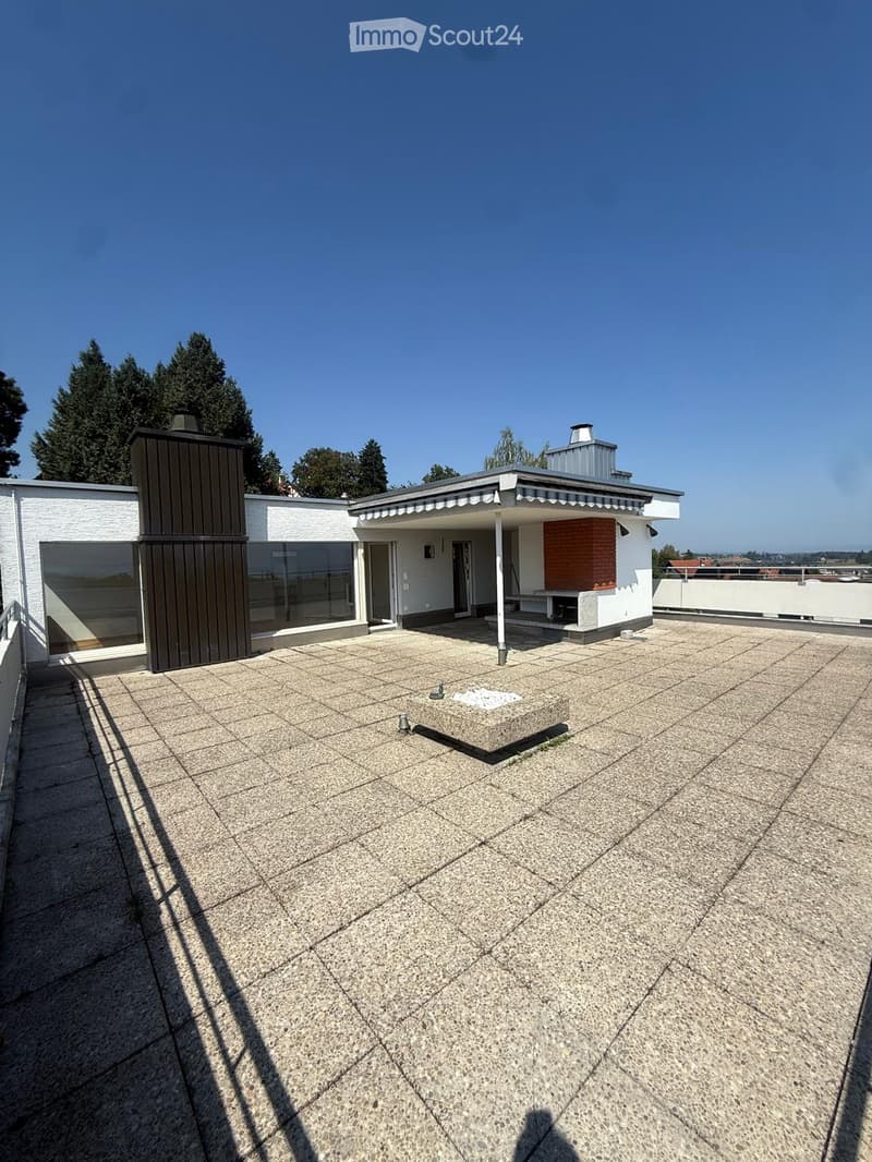Roof terrace with concrete tiles, small square planter, and a small table near the entrance.