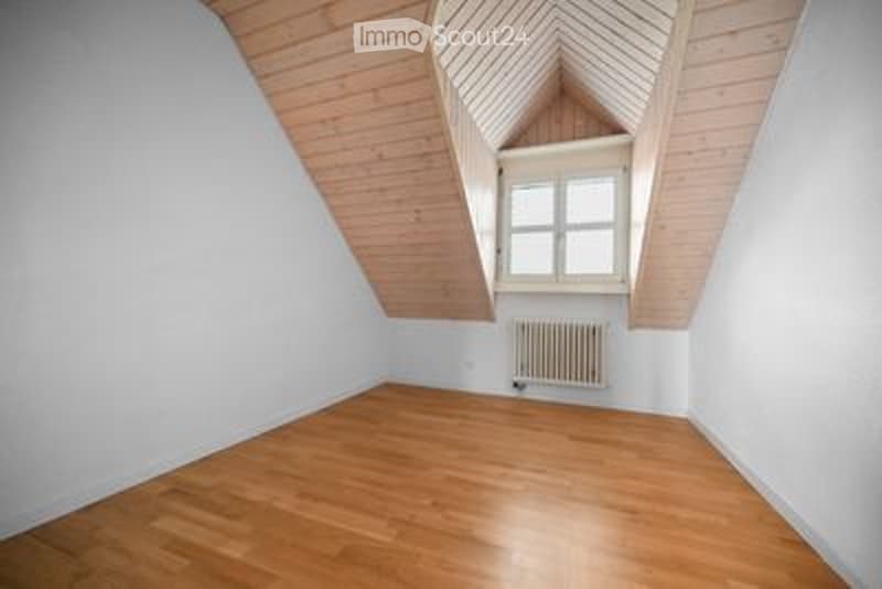 Bright, empty attic room with wooden floors, white walls, and a skylight window. No furniture or equipment present.