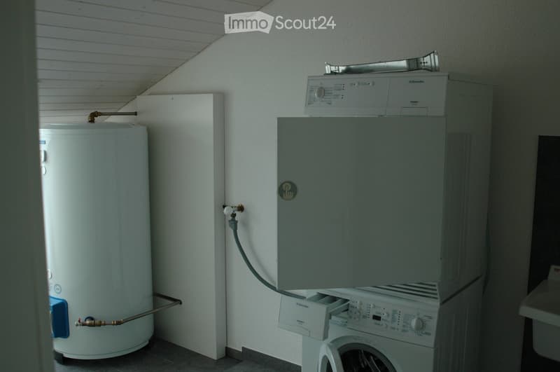 A small utility space with a washing machine and a water heater, both white in color, mounted on the wall.