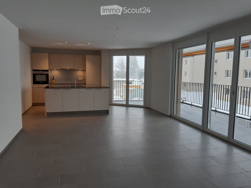 Modern kitchen with light-colored cabinets, a central island, and large sliding glass doors leading to a balcony.