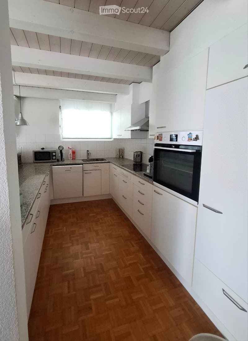 Modern kitchen with white cabinets, granite countertops, wooden flooring, and stainless steel appliances including an oven, dishwasher, and microwave.