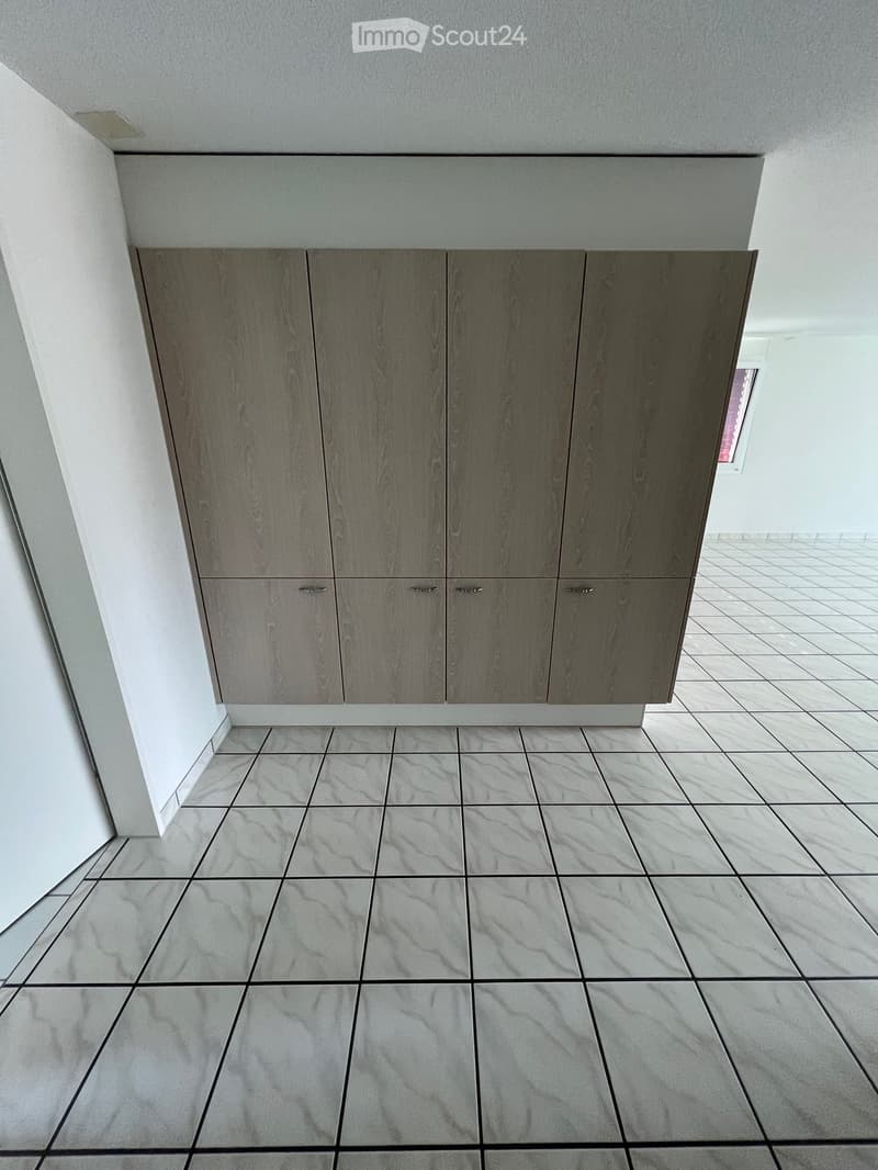Empty room with grey tiled floor and grey cabinetry along one wall. No furniture or equipment present.