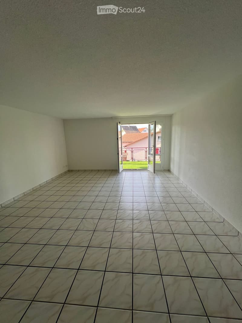 Empty room with tiled floor and white walls, featuring an open doorway leading outside.