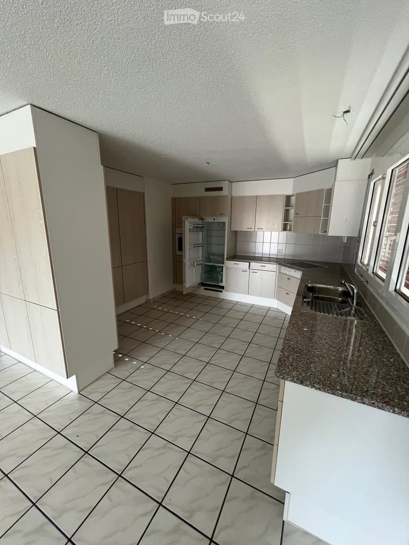 Modern kitchen with white cabinets, granite countertop, tiled floor, and stainless steel sink.