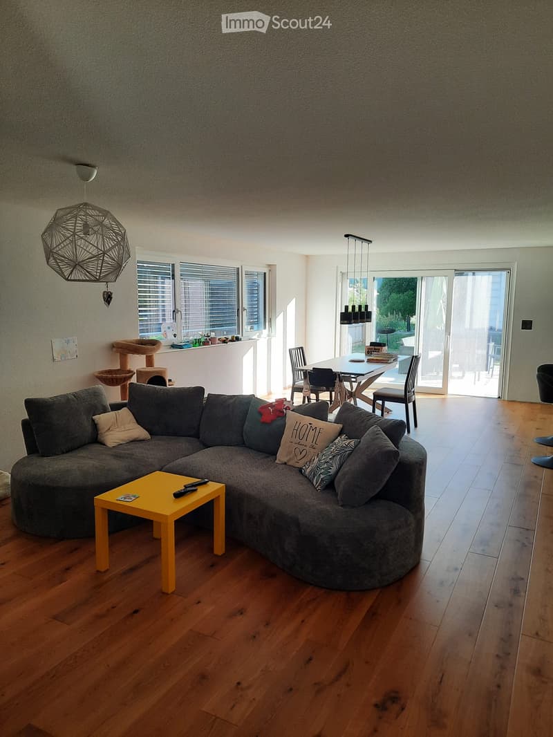 Living room with a large sectional sofa, yellow coffee table, dining area with chairs and table, cat tree, and modern lighting.