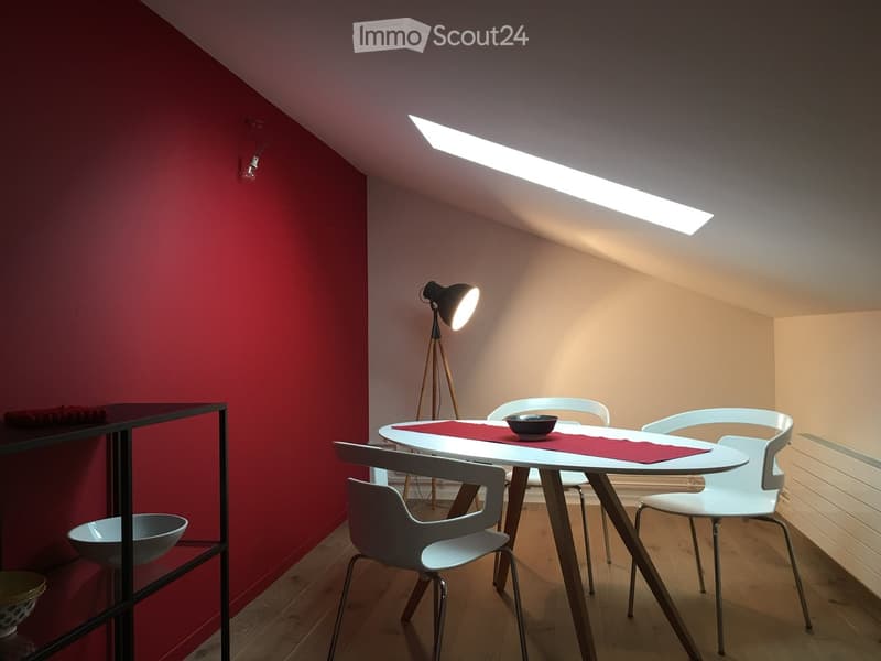 Modern dining area with a white table, four white chairs, a floor lamp, and a shelf with decorative bowls.