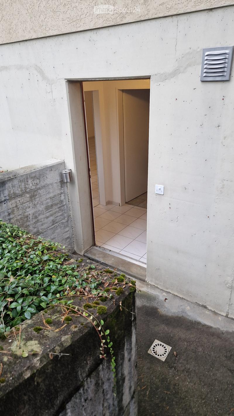 A narrow, raised entranceway leading into a building, with tiled flooring and white walls.