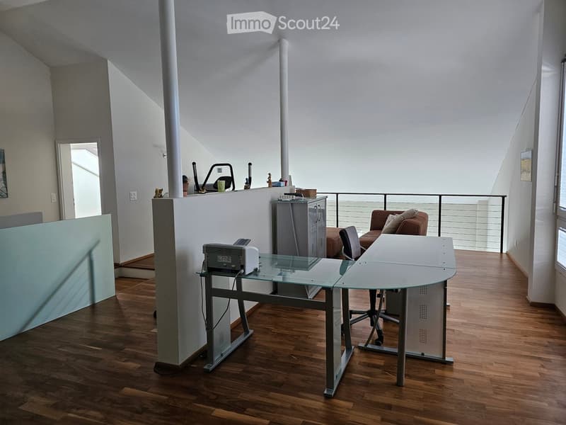 Glass desk, metal office chair, printer, large windows, railings, hardwood floors, cabinets