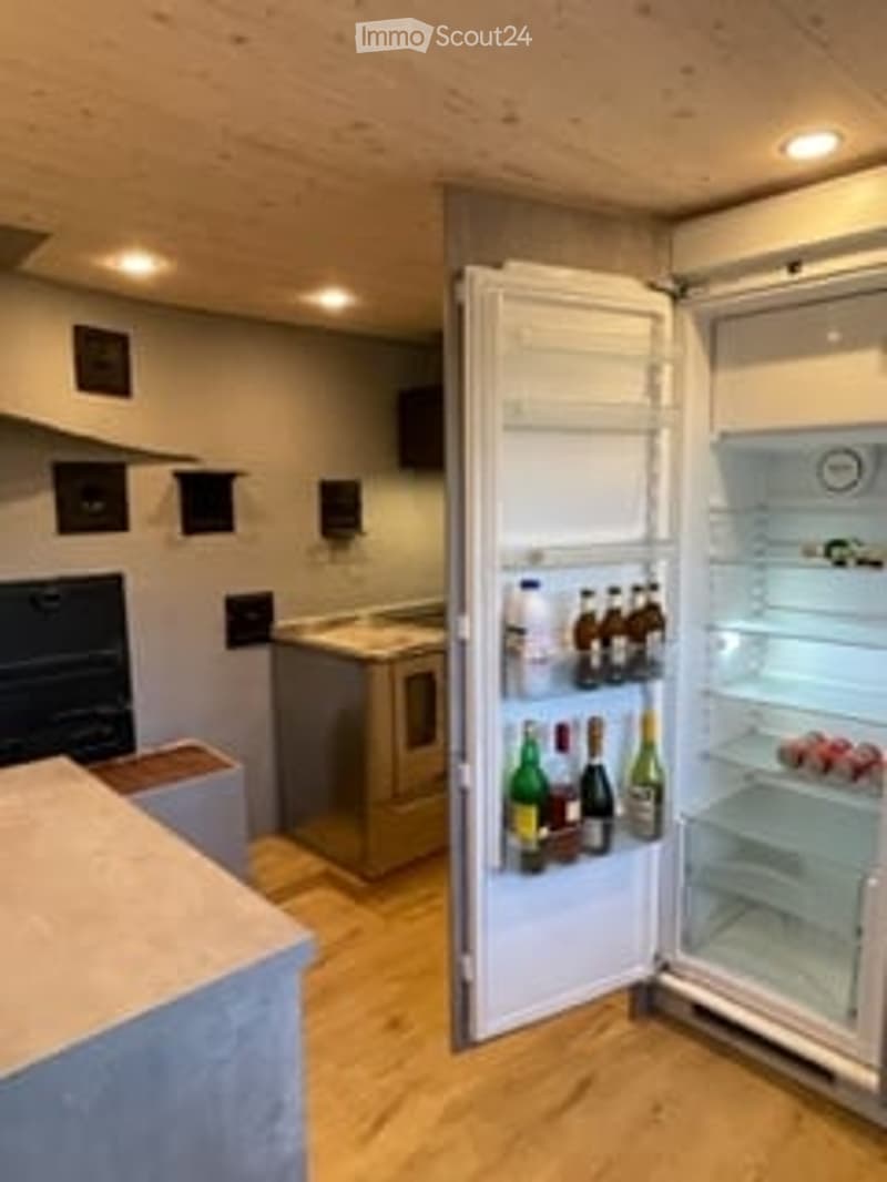 Open kitchen with island, fridge, bottles of wine, wooden floor