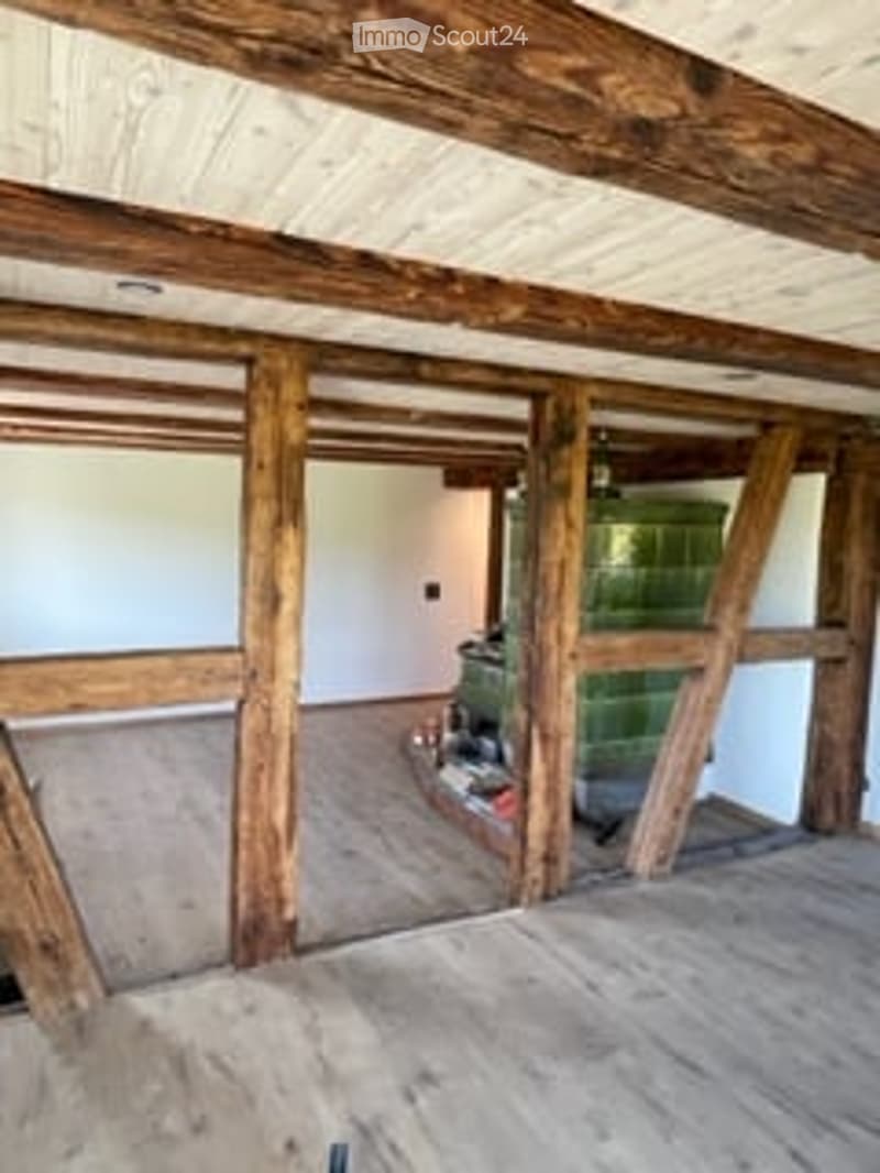 wooden floor, wooden beams, fireplace in corner, unfinished room