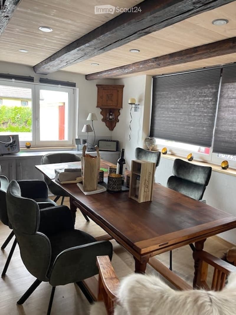 dining area, large wooden table, chairs, wooden beam ceiling, white walls, open windows, kitchen area, windows with blinds