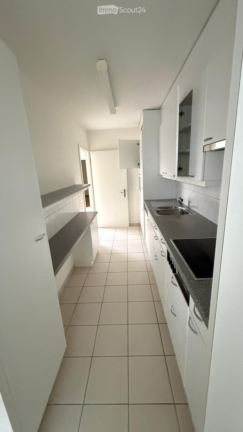 Modern kitchen with white cabinets, tiled floor, and countertop featuring a sink and faucet.
