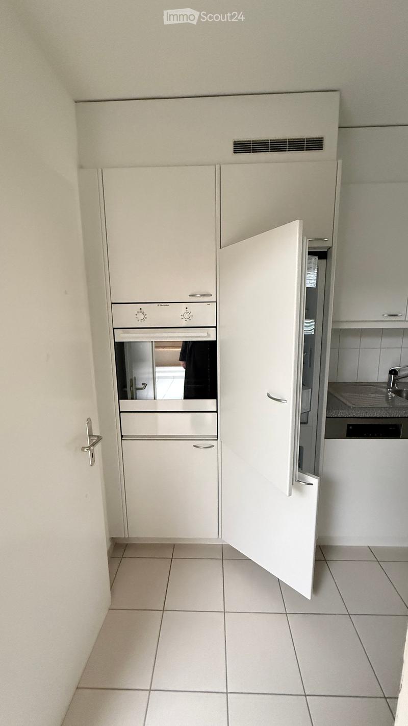 Modern kitchen with white cabinets, a built-in refrigerator, and an oven. The space features tiled flooring and a sleek, contemporary design.