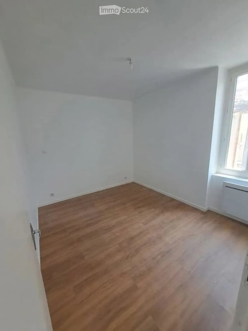 Empty room with wooden flooring and white walls, featuring a window and a door.
