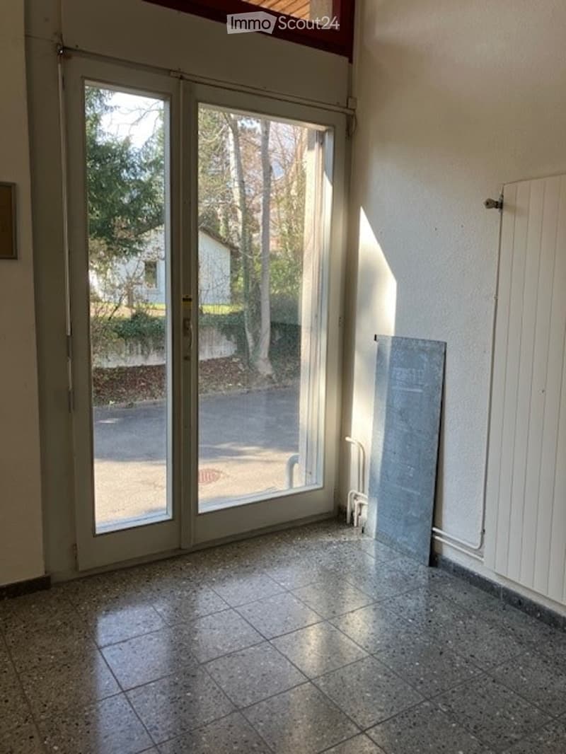 Empty room with sliding glass doors, tiled floor, white walls, and a radiator on the right side.
