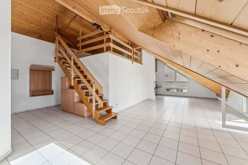 Bright, open room with wooden staircase leading to an upper level, white tiled floor, white walls, and wooden ceiling beams. The space is empty with no furniture.