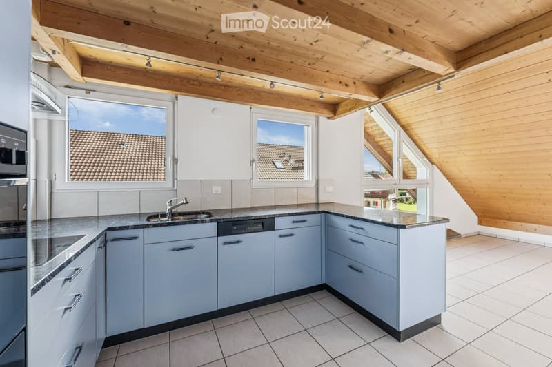 Modern kitchen with light blue cabinets, granite countertops, stainless steel appliances, and large windows offering a view of the roof.