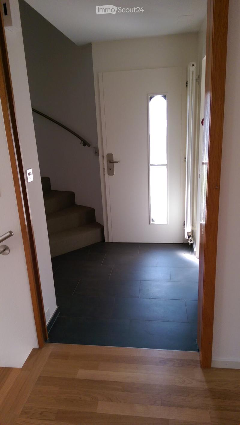 Hallway with wooden flooring, a staircase leading upwards, and a white door with a frosted glass panel.
