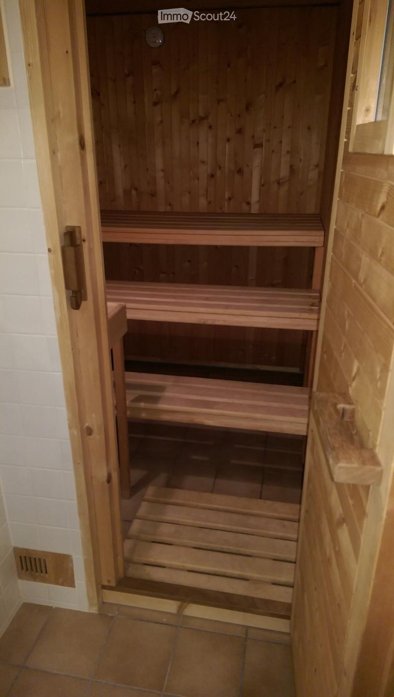 Wooden sauna with multiple wooden benches and a door leading into the room.