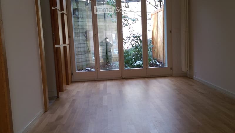 Empty room with wooden flooring and large glass doors leading to an outdoor area.