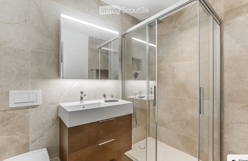 Modern bathroom with a white sink, mirrored cabinet, and a glass-enclosed shower stall.