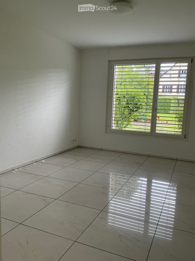 Empty room with white walls, tiled floor, and a large window with blinds. No furniture or equipment present.
