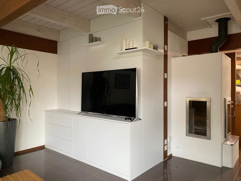 Modern living room with a white cabinet, television, fireplace, and decorative shelves.