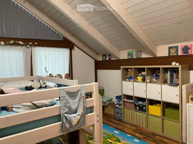 Cozy children's bedroom with a bunk bed, storage unit, toys, and artwork on the walls.