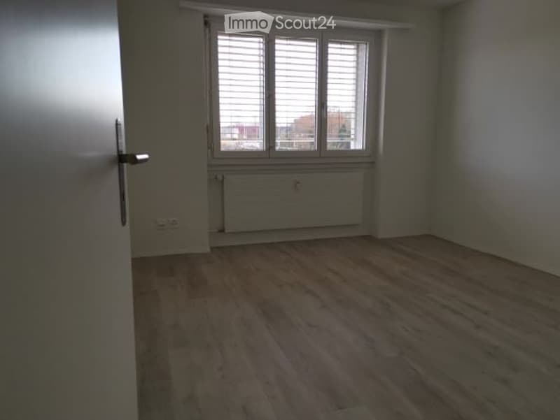 Empty room with wooden flooring, white walls, and a window with blinds. No furniture or equipment is present.