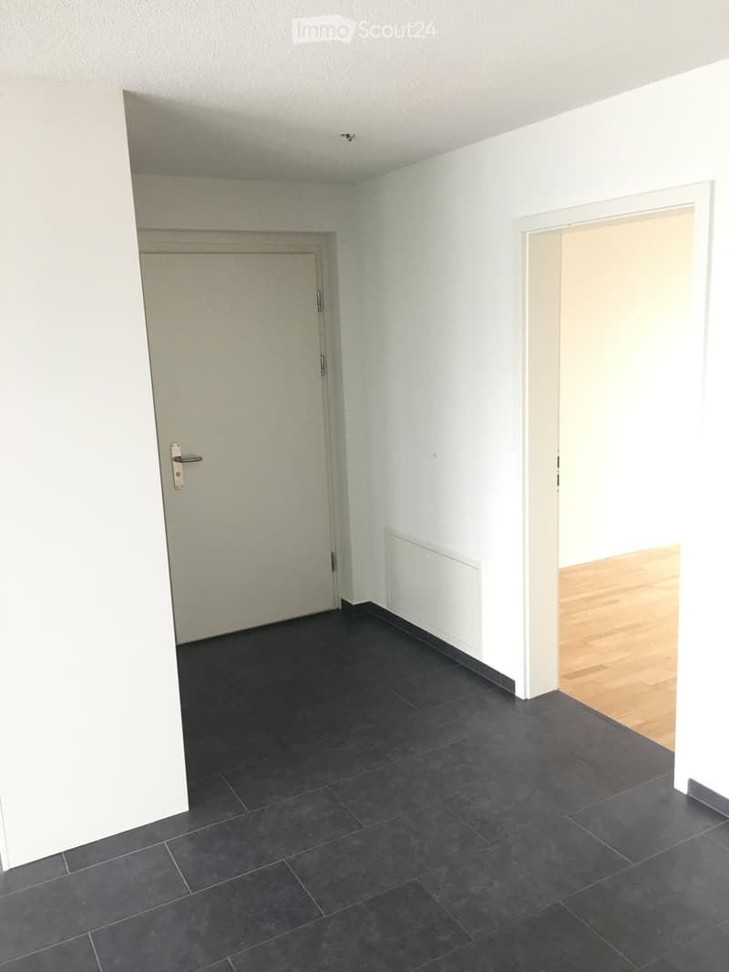 empty room, white walls, black tile floor, closed door, open doorway to another room, wooden floor