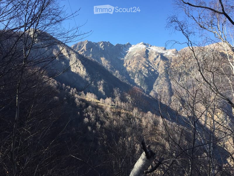 Mountainous landscape with snow-capped peaks, rocky terrain, and sparse vegetation.