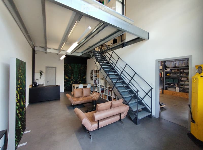 Modern living room with a staircase leading to an upper level, featuring a sofa, chairs, coffee table, bookshelf, and a small kitchen area with a sink and cabinet.