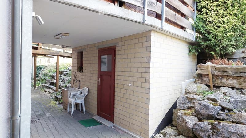 Outdoor area with a brick wall, small seating area, and decorative rock formations.