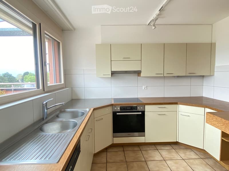 Modern kitchen with light-colored cabinets, a double sink, and an oven. The space features wooden countertops and tiled flooring.