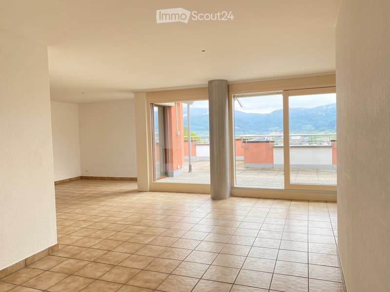 Empty room with tiled floor, large windows, and scenic mountain view.