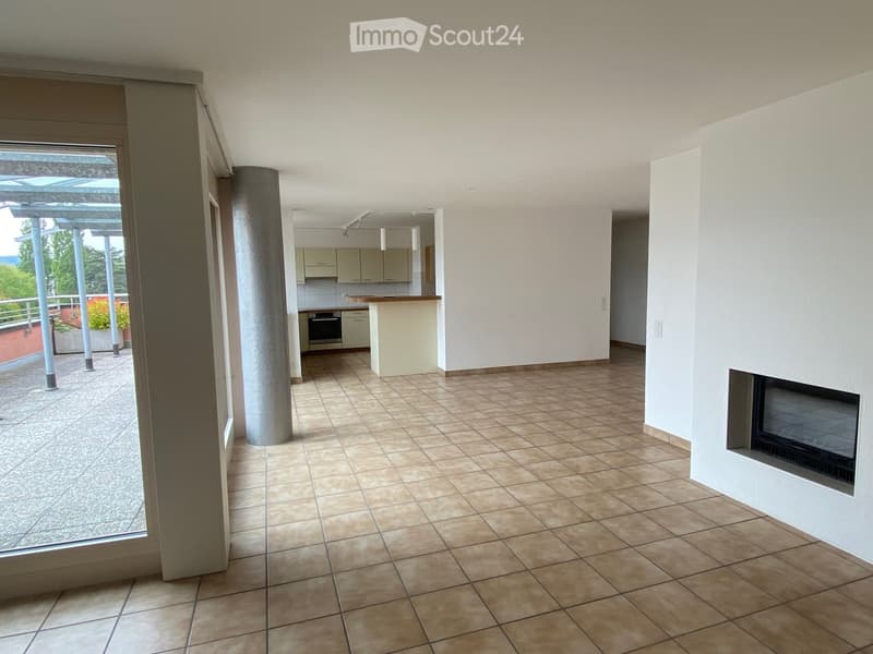 Open-plan living and dining area with tiled flooring, fireplace, and a kitchen area with cabinets and an island.