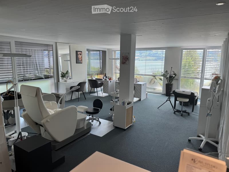 Modern, well-lit salon with multiple client chairs, a reception desk, and various treatment areas.