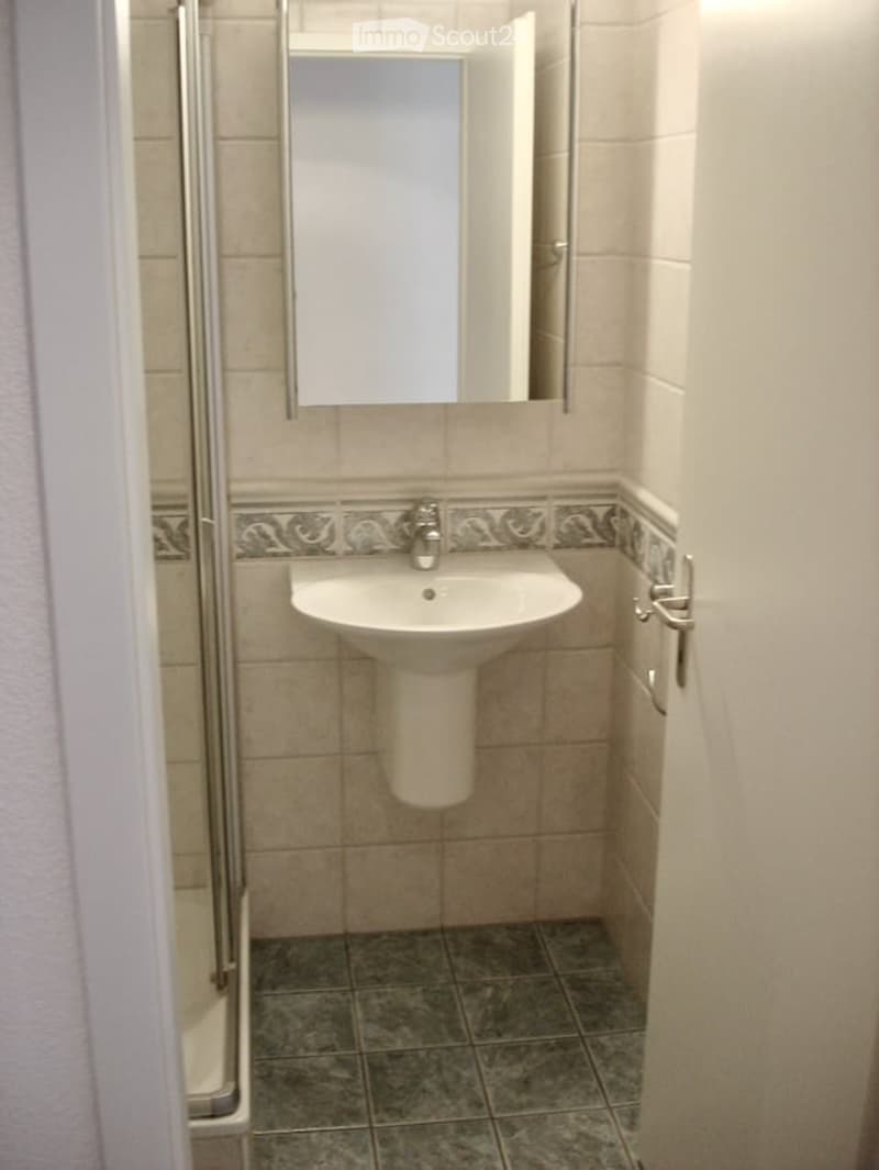 Small bathroom with a white sink, mirror, and tiled walls and floor.