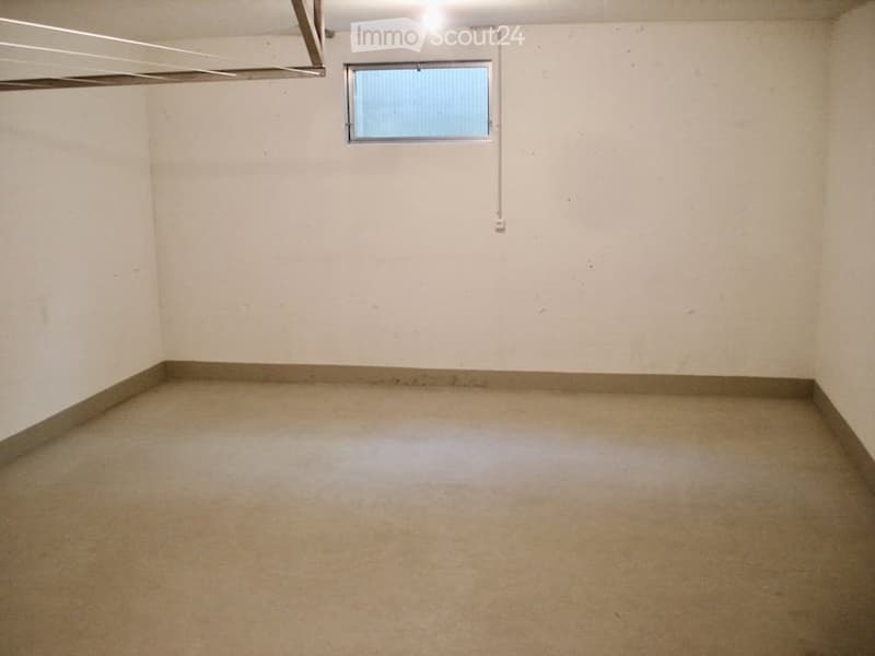 Empty room with concrete floor, white walls, and a small window with blinds. No furniture or equipment present.