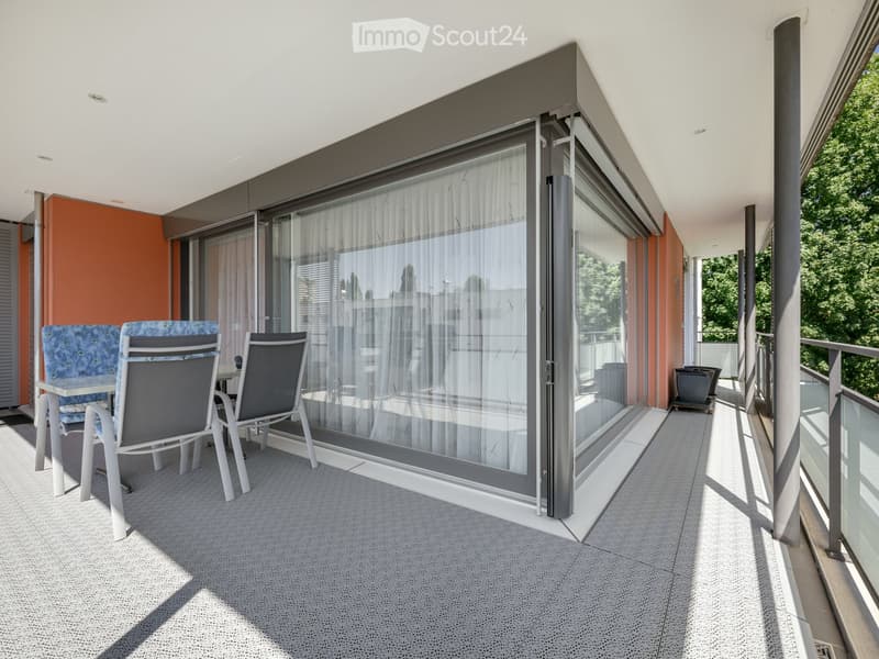 Balcony with grey tiled floor, white sliding glass doors, and a small table with four chairs.