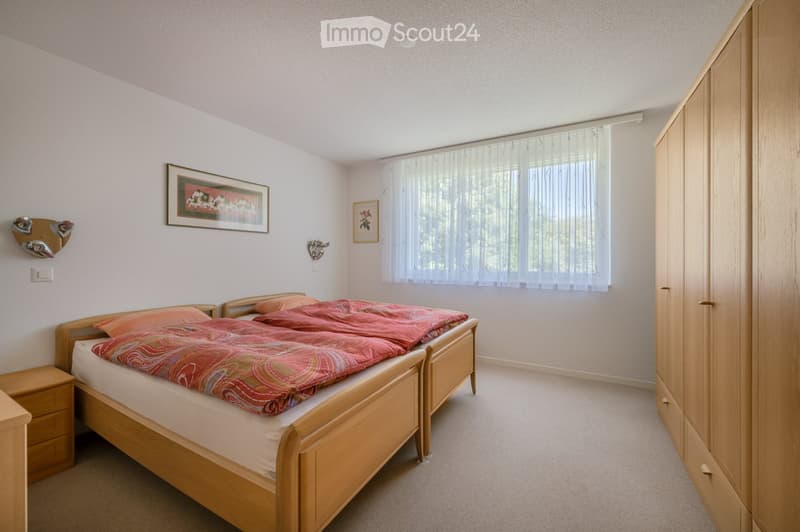 Cozy bedroom with a double bed, wooden wardrobe, nightstand, and framed artwork on the walls.