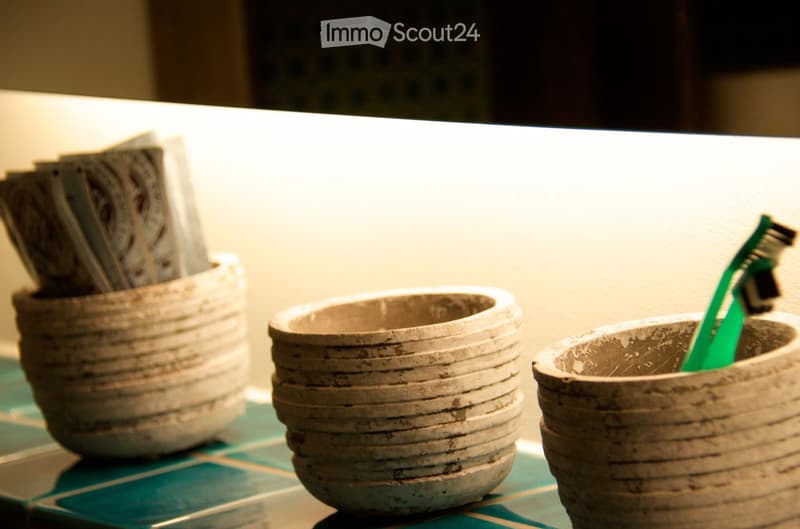 Three ceramic cups on a bathroom counter, one holding a toothbrush.