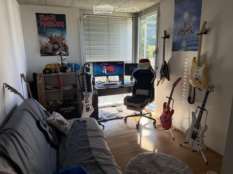 A multi-purpose room with a sofa, desk, gaming chair, multiple guitars, posters, and a shelf with various items.