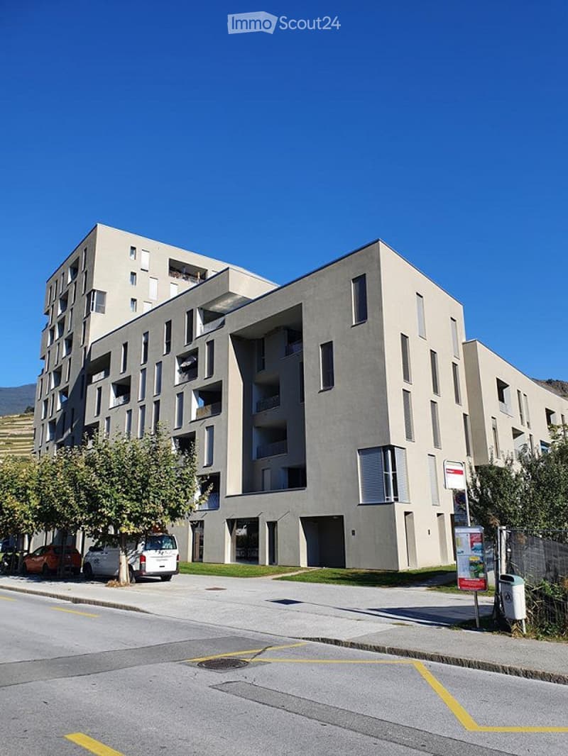 Modern multi-story residential building with a clean, contemporary design, featuring balconies and large windows.